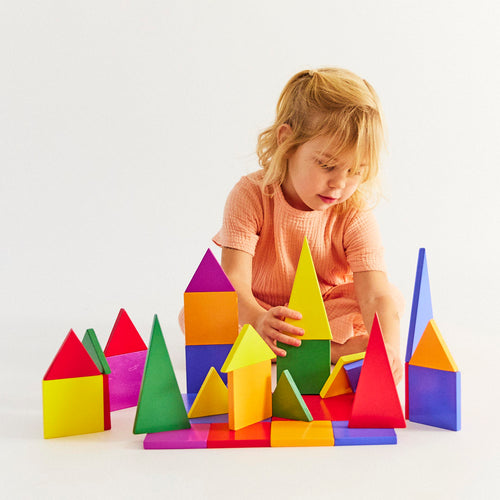 Child in a peach dress building with colorful wooden magnetic tiles